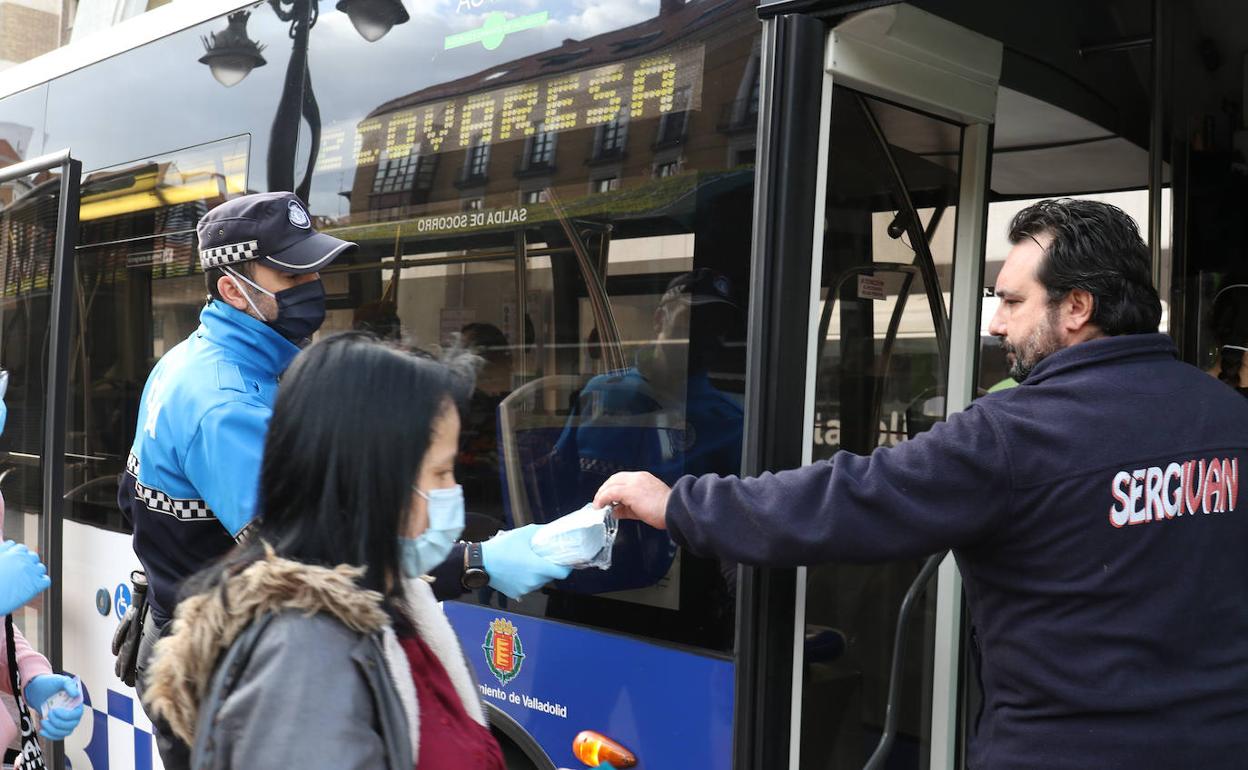 Un agente entrega una mascarilla a un pasajero.