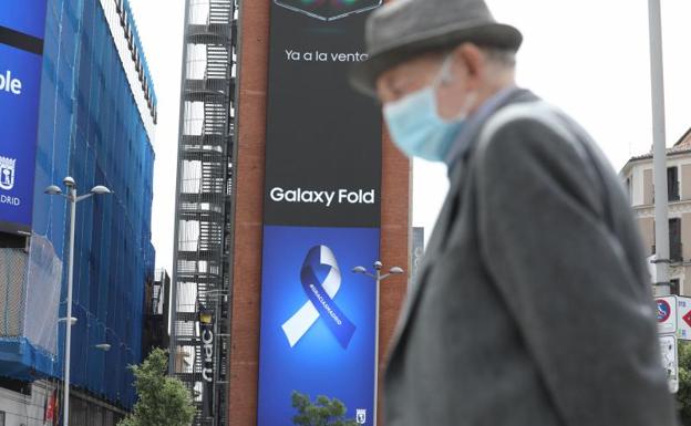 Un hombre pasea por Madrid junto a carteles sobre la Covid-19- 