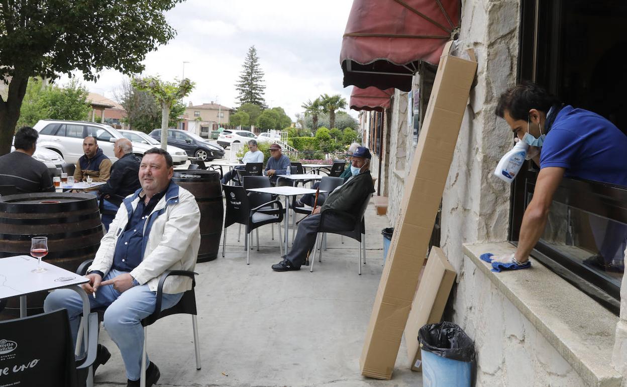 Un hombre limpia en un bar de Torquemada (Palencia), ayer, mientras los vecinos disfrutan de la terraza. 