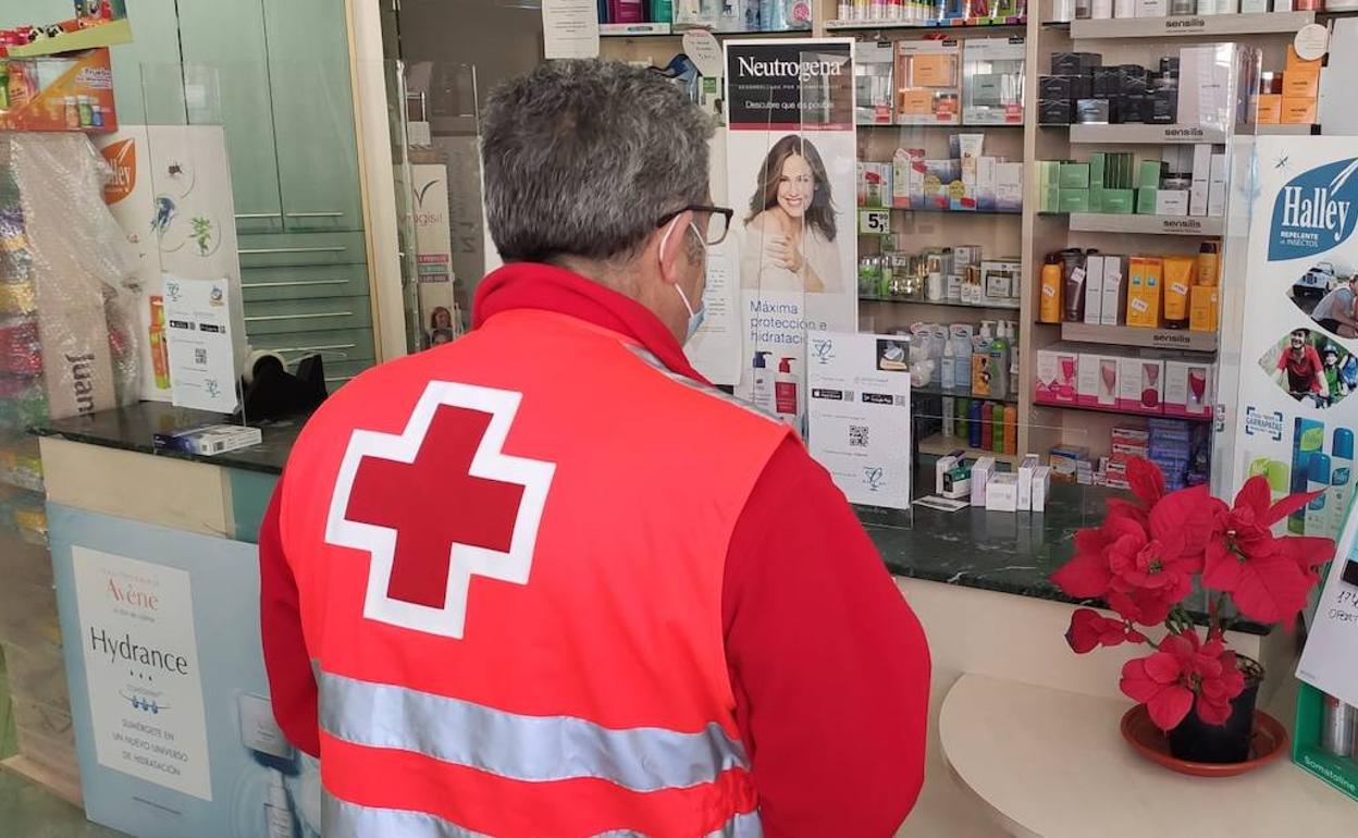 Un voluntario de Cruz Roja recoge medicamentos en una farmacia.