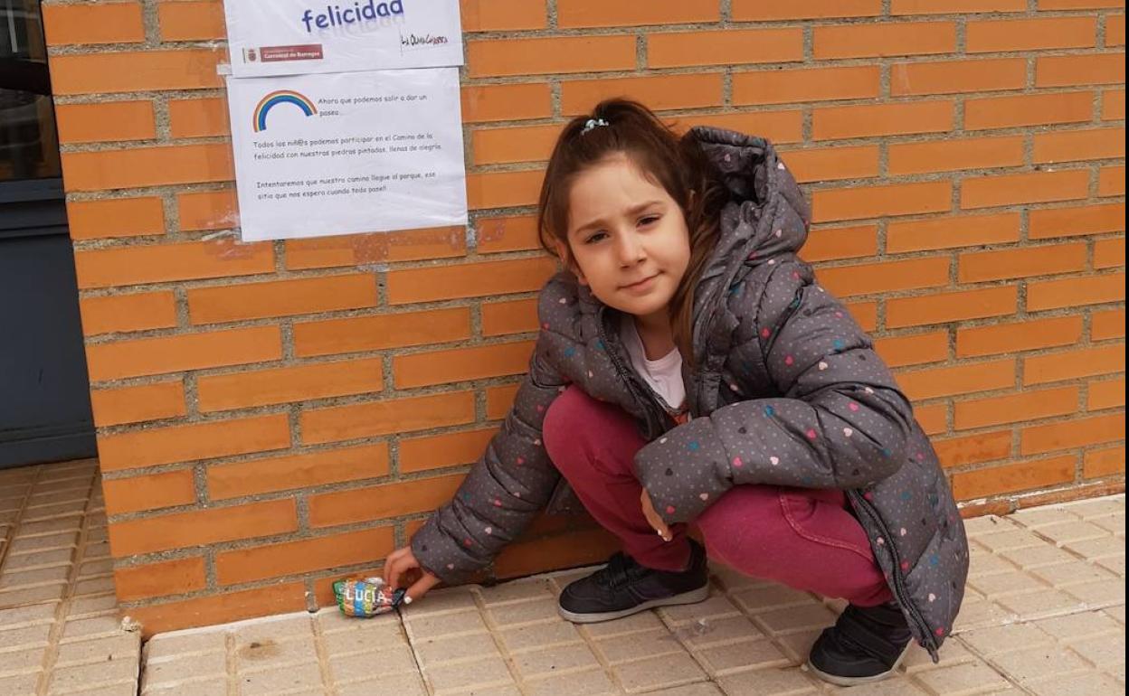 Una niña deposita su piedra decorada. 