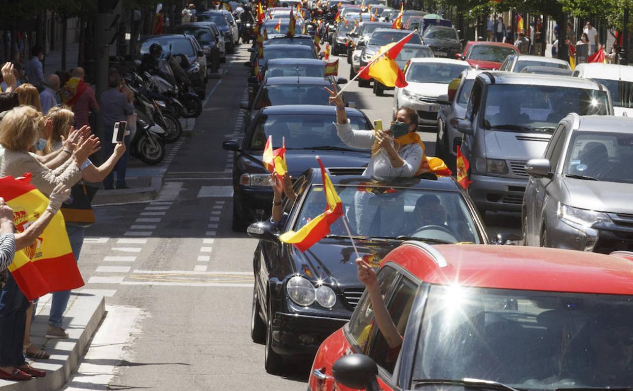 Una mujer graba con el móvil asomada por el techo solar del coche, durante la caravana por Valladolid. 