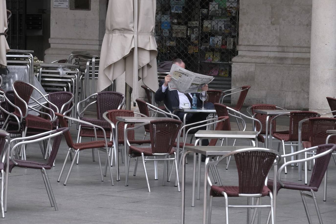 Un señor lee el periódico en una terraza de la Plaza Mayor. 