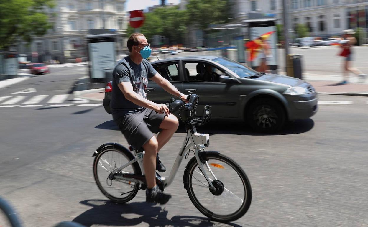 Un ciclista circula entre el tráfico a motor por la madrileña plaza de Cibeles.