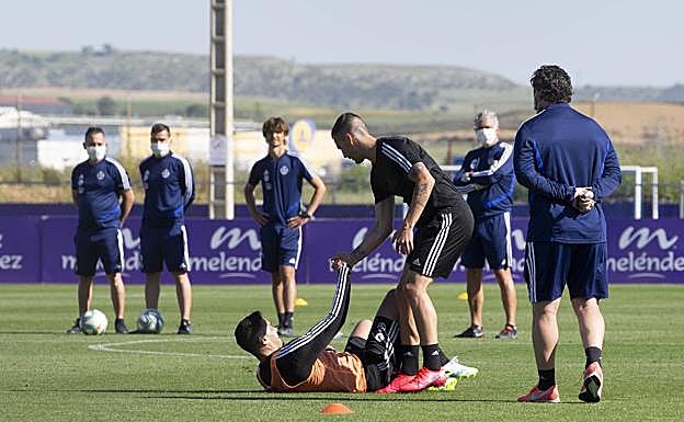 Guardiola ayuda a levantar a Waldo en un entrenamiento ante la mirada de Sergio.