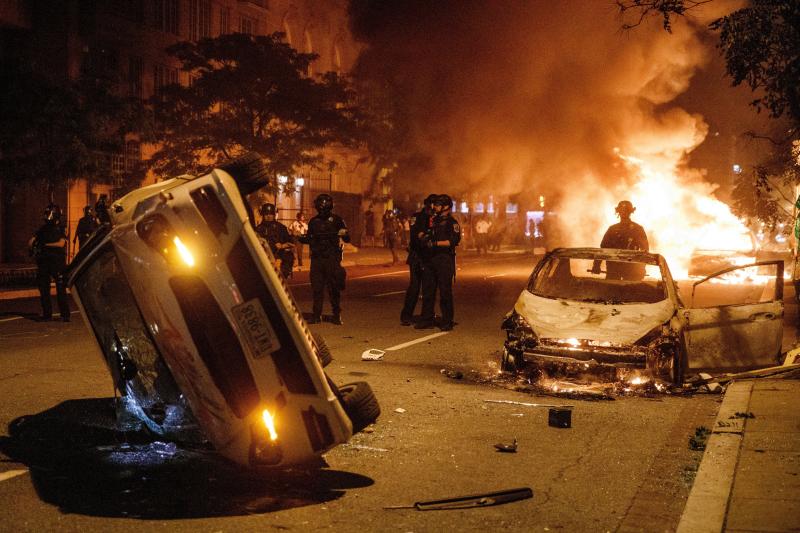 Agentes de policía tras dos coches incendiados durante una de las protestas en Washinton.