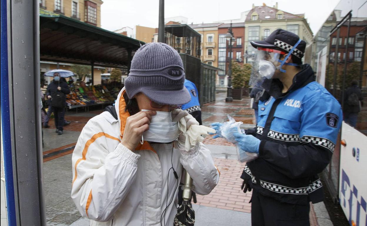 Un agente entrega mascarillas a los usuarios del autobús.