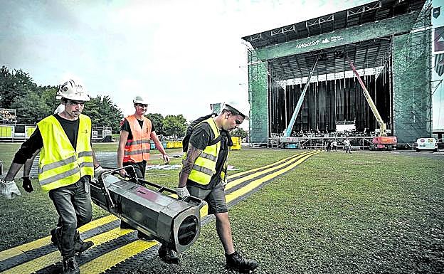 Técnicos trasladan un foco durante el montaje de un festival.