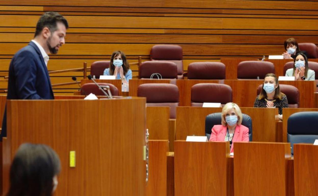 Luis Tudanca inverviene en las Cortes, aplaudido por procuradoras socialistas, mientras la consejera de Sanidad escucha sus argumentos.