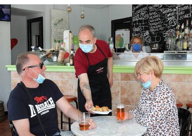 Imagen secundaria 1 - Arriba y abajo a la derecha, dos clientes en una mesa y el cartel en el que se explica que la barra está fuera de servicio por el momento en Los Zagales. Abajo a la izquierda, dos ciudadanos toman unas tapas en el Bar Mini Circular. 