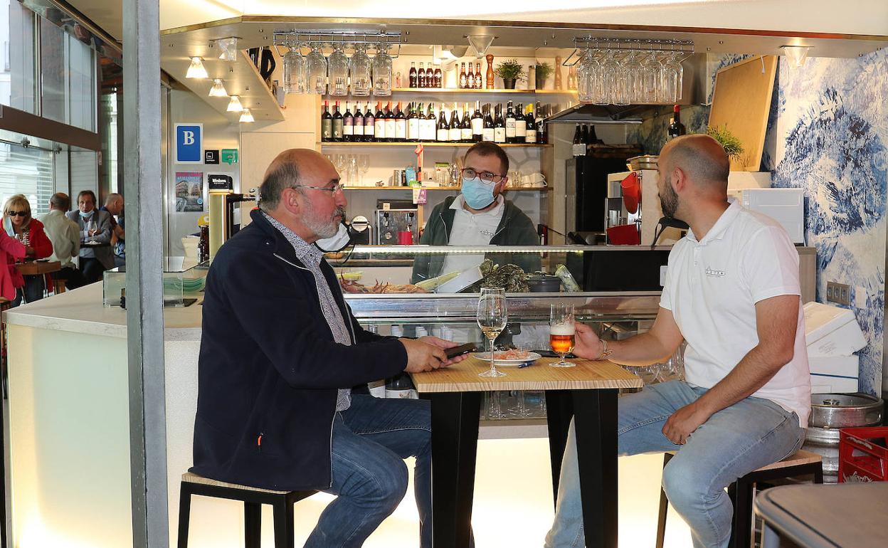 Dos clientes sentados a una mesa junto a la barra del gastropuesto Austral del Mercado del Val. 