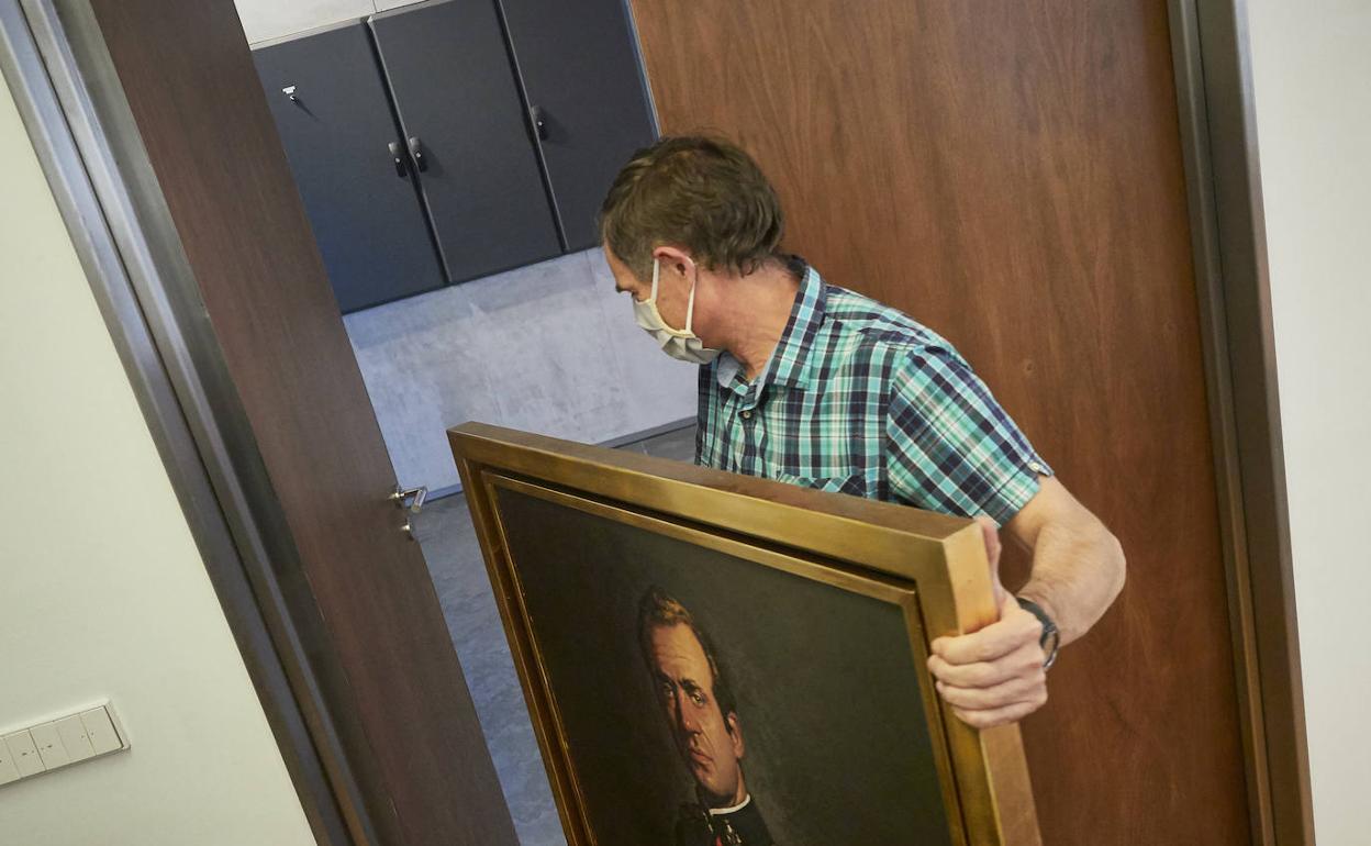Un operario retira un cuadro de Juan carlos I del Parlamento de Navarra.