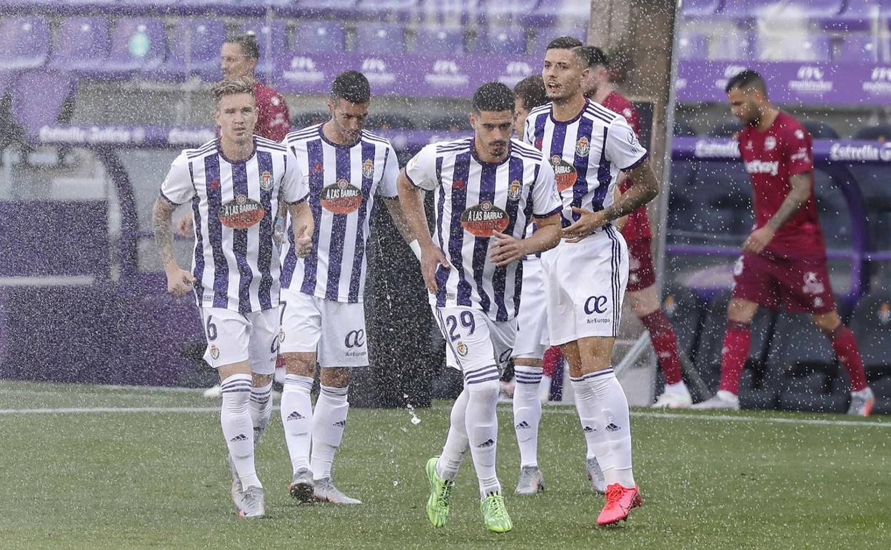 Los jugadores, tras los aspersores antes del partido.