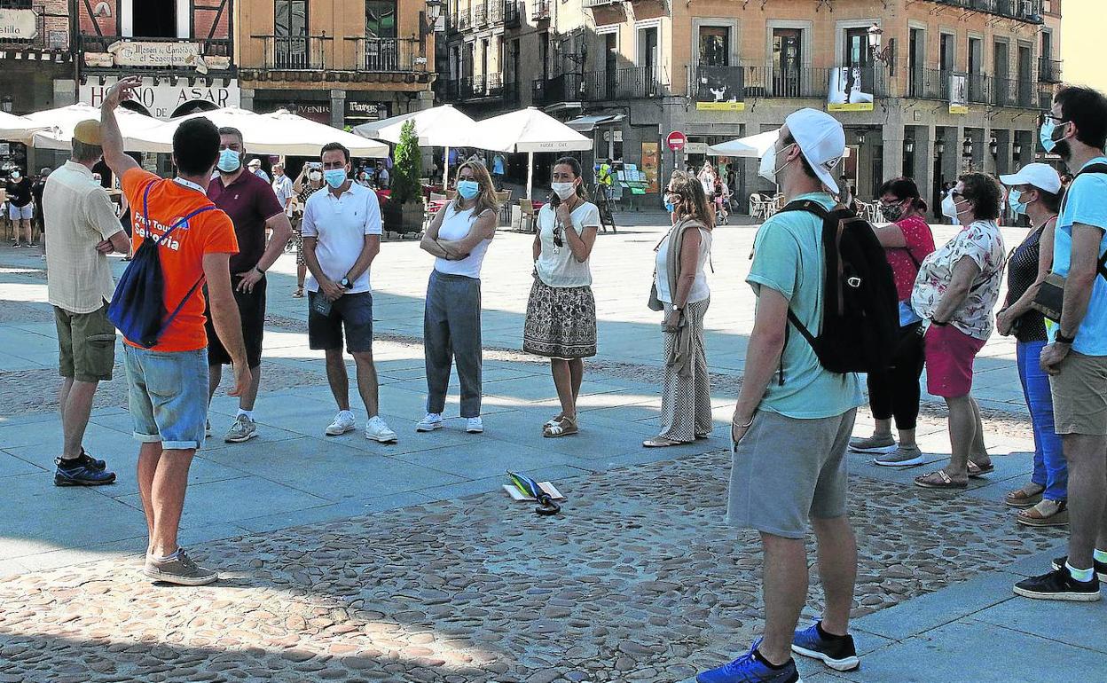 Un grupo de turistas escuchan las explicaciones de un guía en la plaza del Azoguejo, junto al Acueducto. 