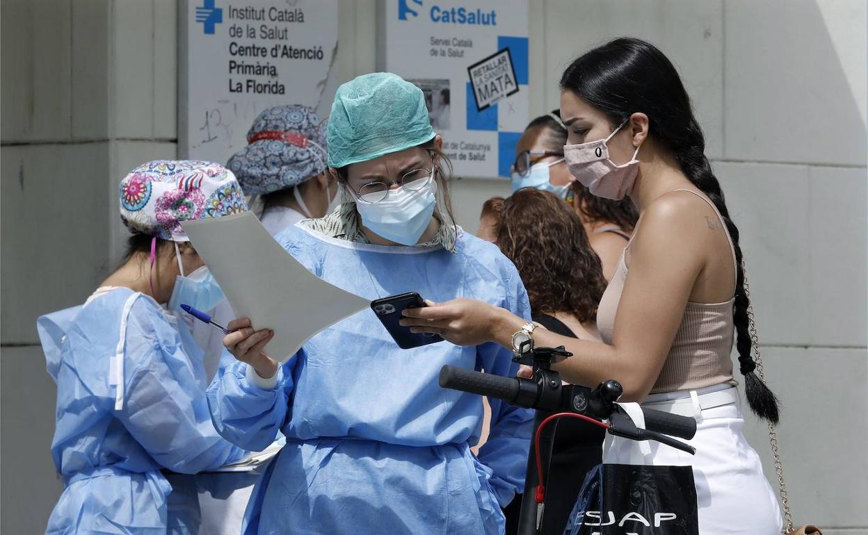 Una enfermera comprueba la cita previa de una mujer en la puerta del Centro de Atención Primaria del barrio de la Florida de L´Hospitalet (Barcelona).