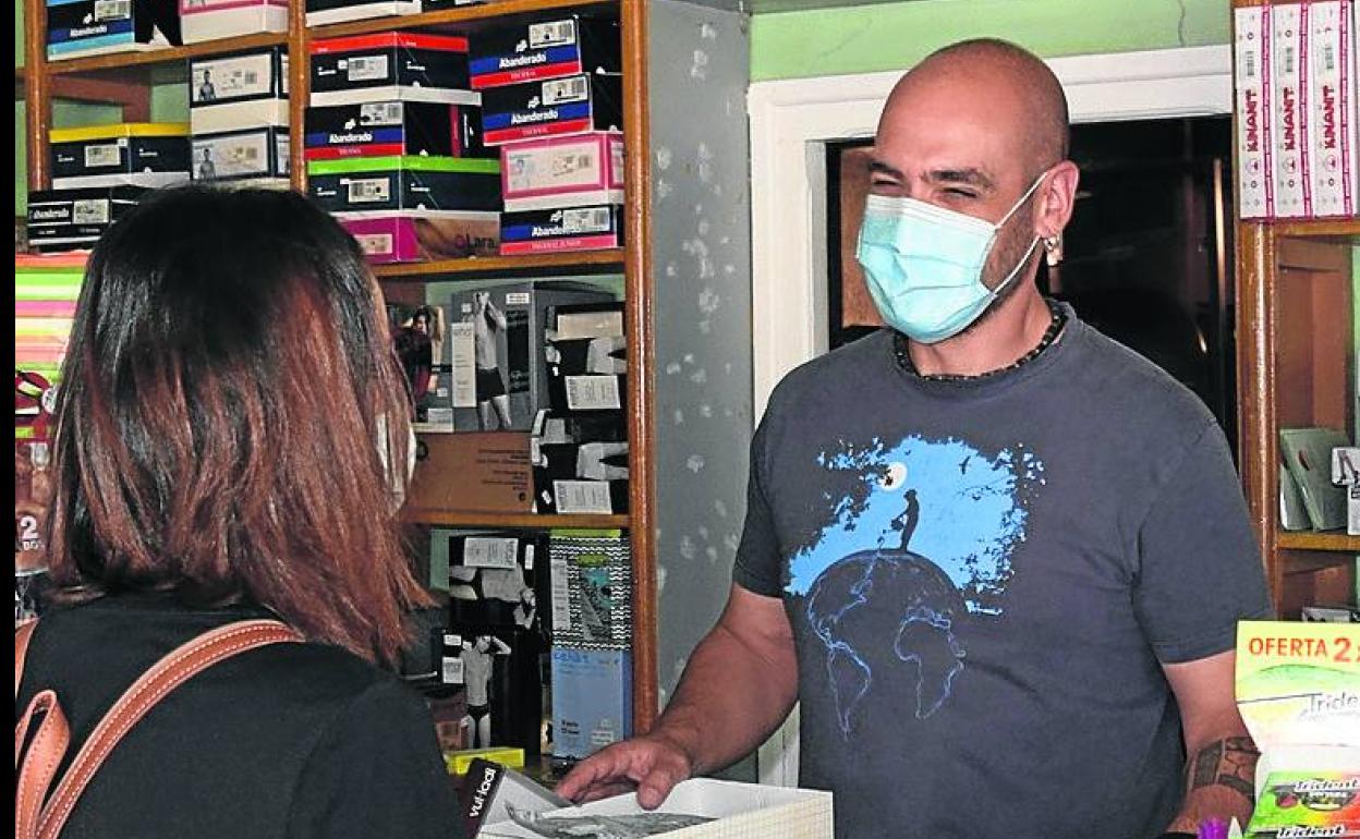 Adrián Pérez Allende atiende a una cliente en el estanco de la localidad palentina de Velilla del Río Carrión.