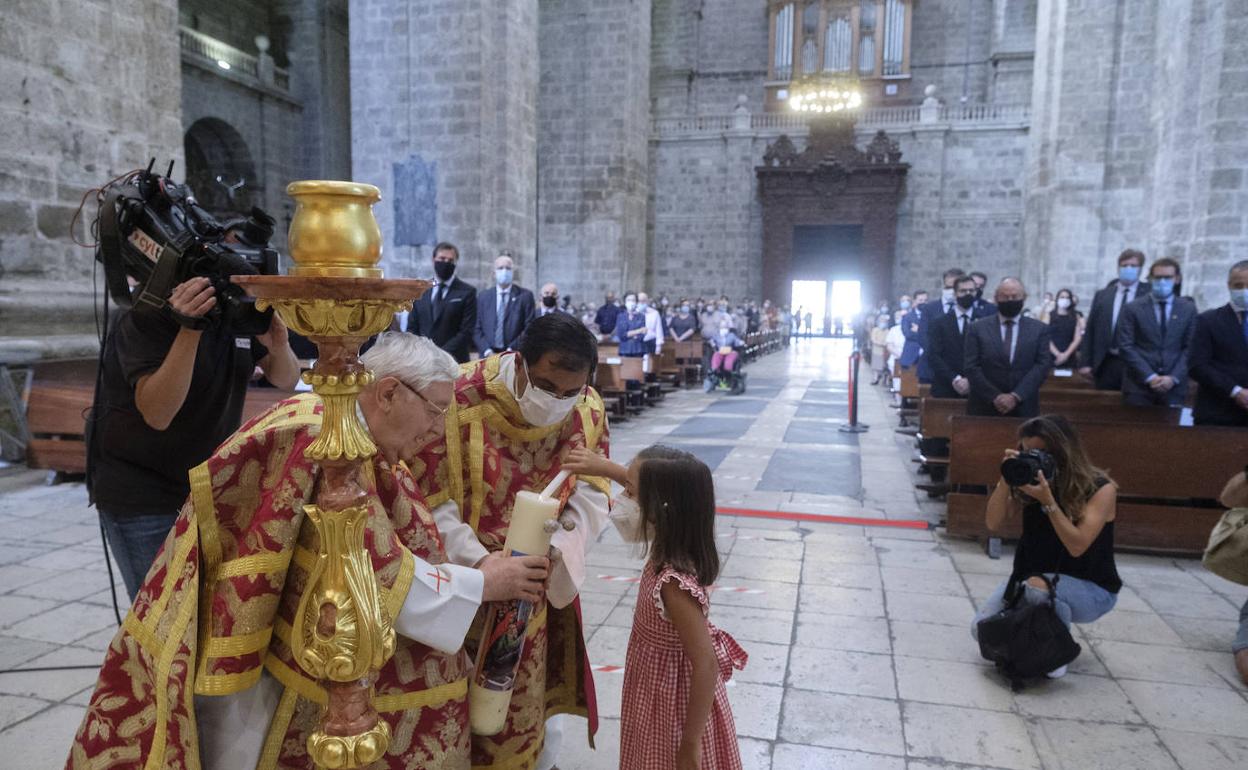 Una niña enciende una vela en la misa funeral por las víctimas de la covid-19, celebrada en la catedral. 