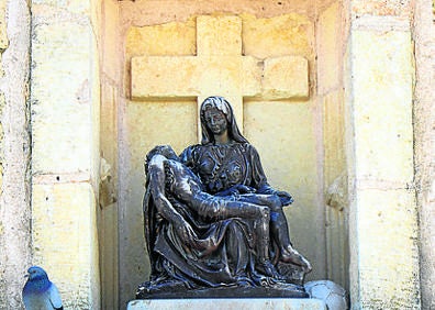Imagen secundaria 1 - Arriba, la iglesia en una vista en la que se aprecia el ábside; Virgen con su Hijo en brazos sobre la puerta de entrada al templo y torre de la iglesia, de estructura medieval.