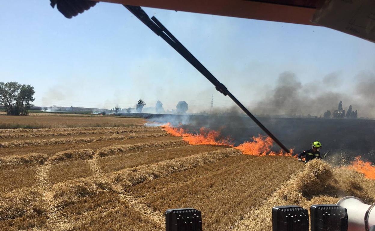 Los bomberos intentan sofocar el incendio en una tierra de cereal.