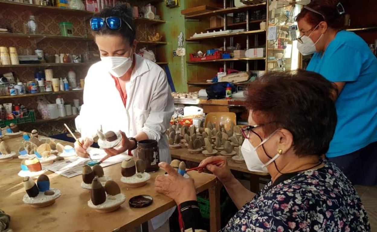 Tres mujeres pintan a mano las piedras en el taller.