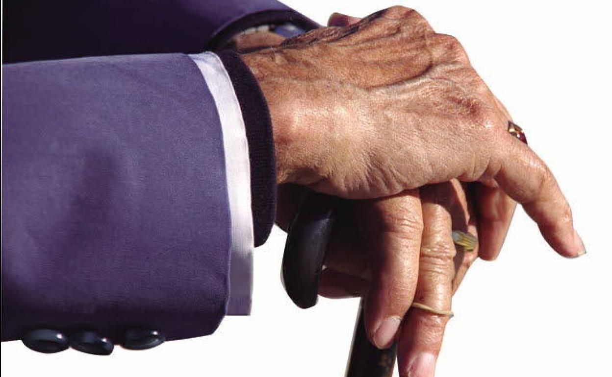 Una persona mayor se apoya sobre un bastón.