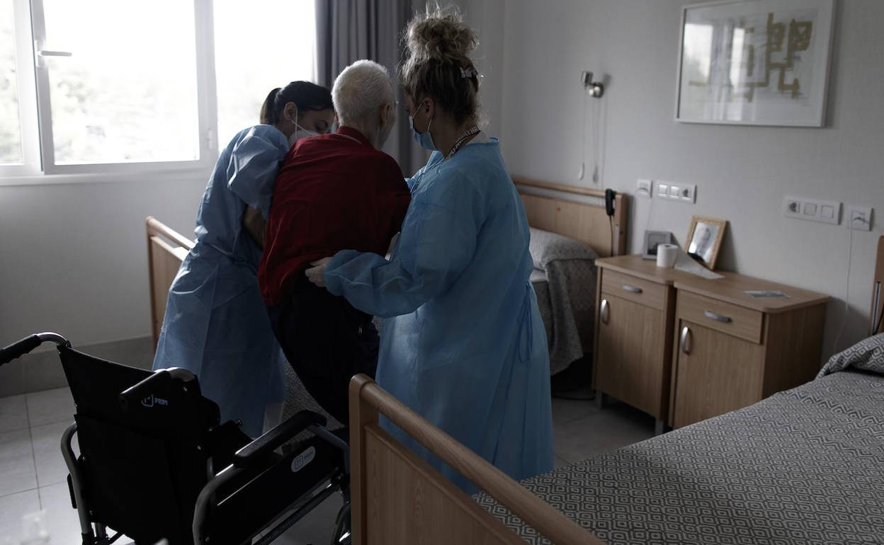 Dos trabajadoras atienden a un anciano en una residencia.