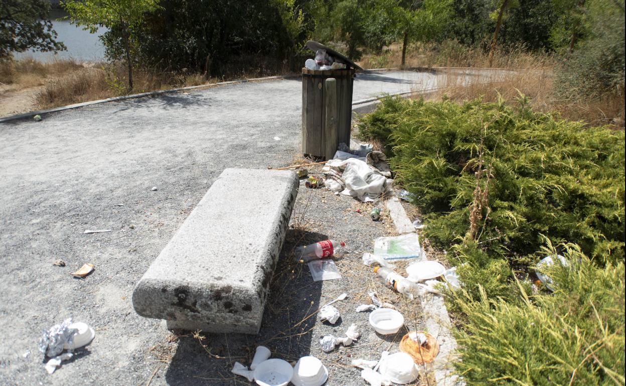 Restos y desechos esparcidos este fin de semana alrededor de un banco una papelera en un camino del área recreativa del Pontón Alto. 