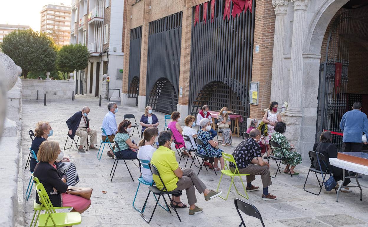 Un grupo de fieles sigue las celebraciones religiosas de la parroquia de San Lorenzo desde la calle. 