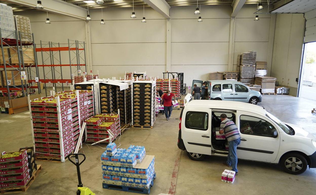 Voluntarios del Banco de Alimentos cargan vehículos de reparto para distribuir suministros.