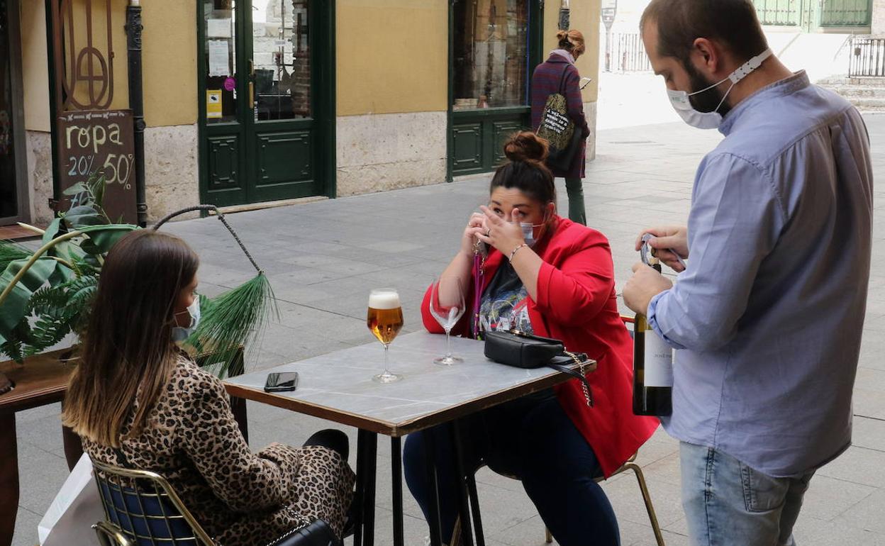 Un camarero atiende a dos jóvenes en una terraza de Valladolid. 