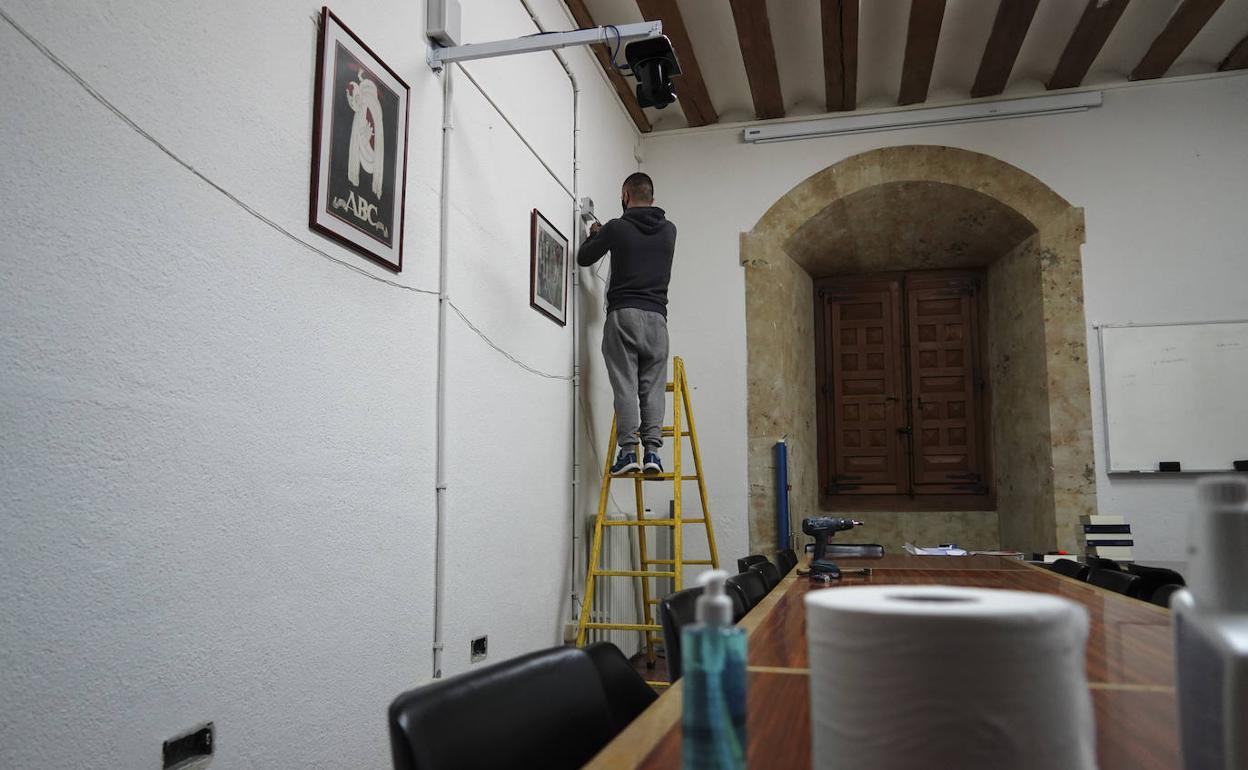 Un operario instala un proyector en un edificio de la Universidad. 