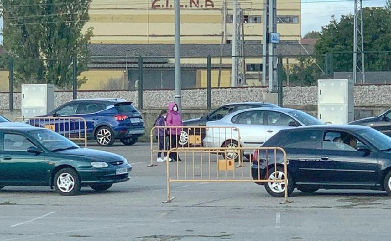 Una mujer y su hija esperan en la cola del estadio Reino de León entre coches y a temperaturas mínimas.