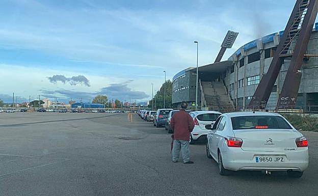 Un hombre hace cola entre los vehículos en el estadio Reino de León.