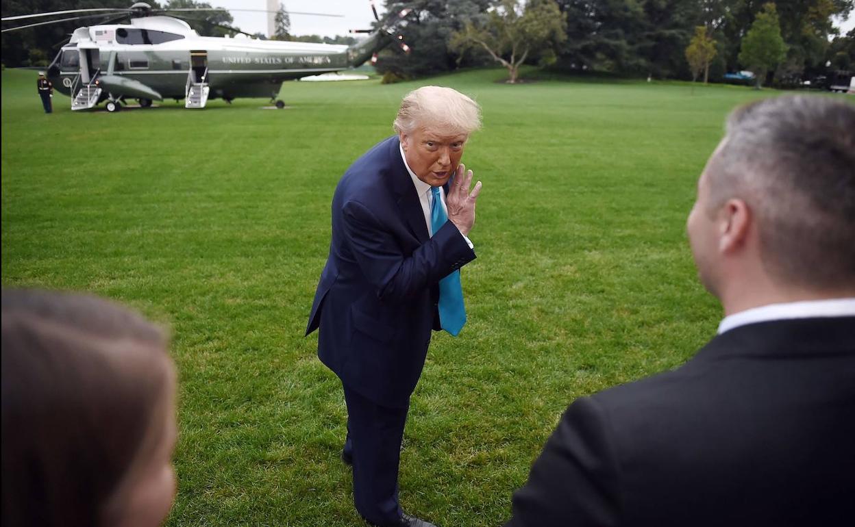 Trump simula hacer una confidencia a los periodistas tras descender de un helicóptero militar en los jardines de la Casa Blanca.