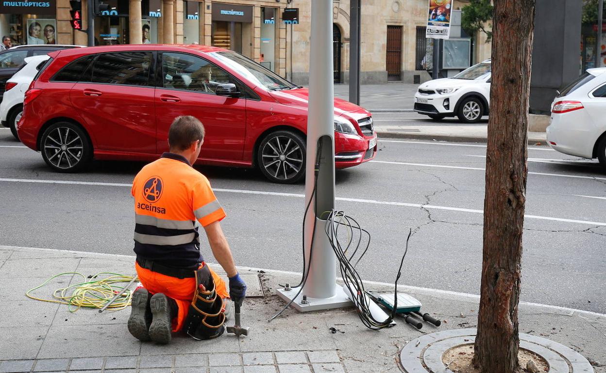 Un operario sustituye el cableado de una farola de la ciudad.