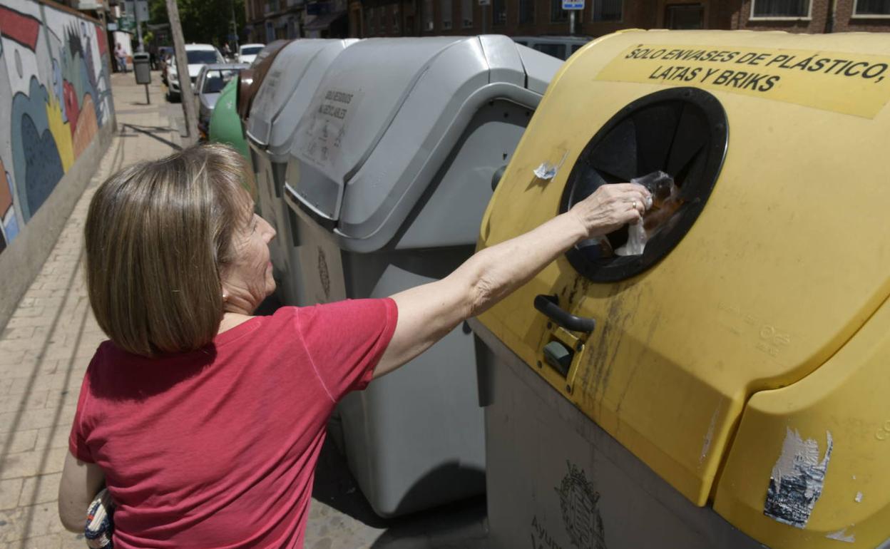 Una mujer deposita residuos en un contenedor amarillo en el barrio vallisoletano de La Victoria.