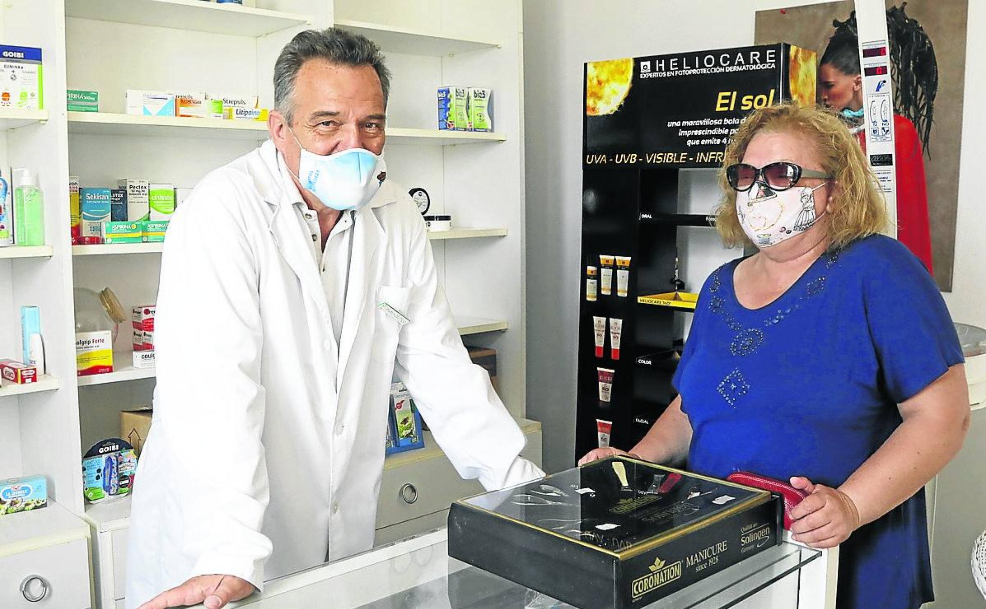 Adolfo González posa en la farmacia de Cervatos con una clienta.