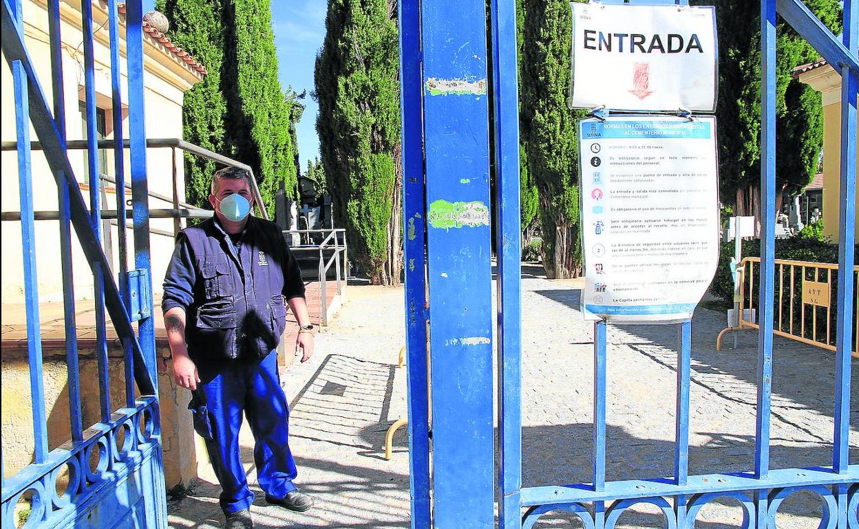 El encargado del cementerio del Segovia, ayer, en la entrada del recinto municipal donde hay un cartel con los consejos de seguridad anticovid. 