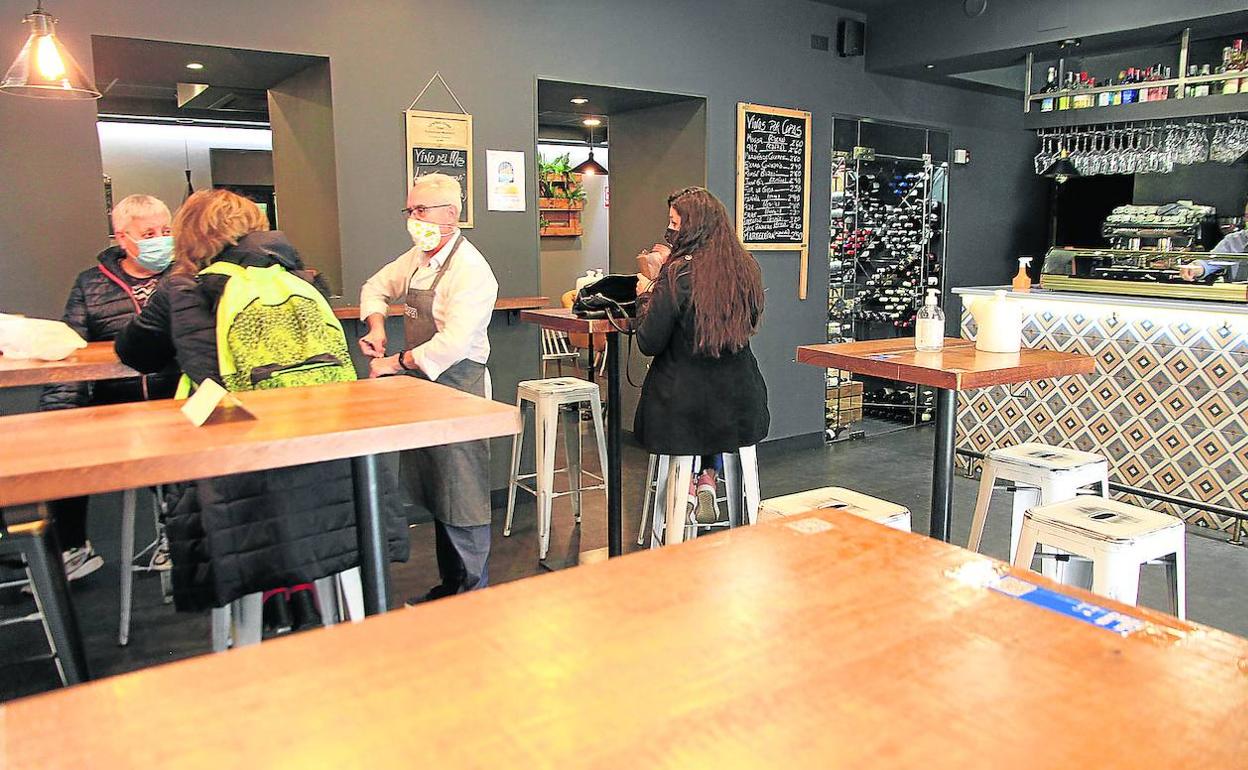 Un camarero atiende a dos clientes, al mediodía de ayer, en el restaurante Pasapán, que ha despejado de sillas y mesas la barra. 