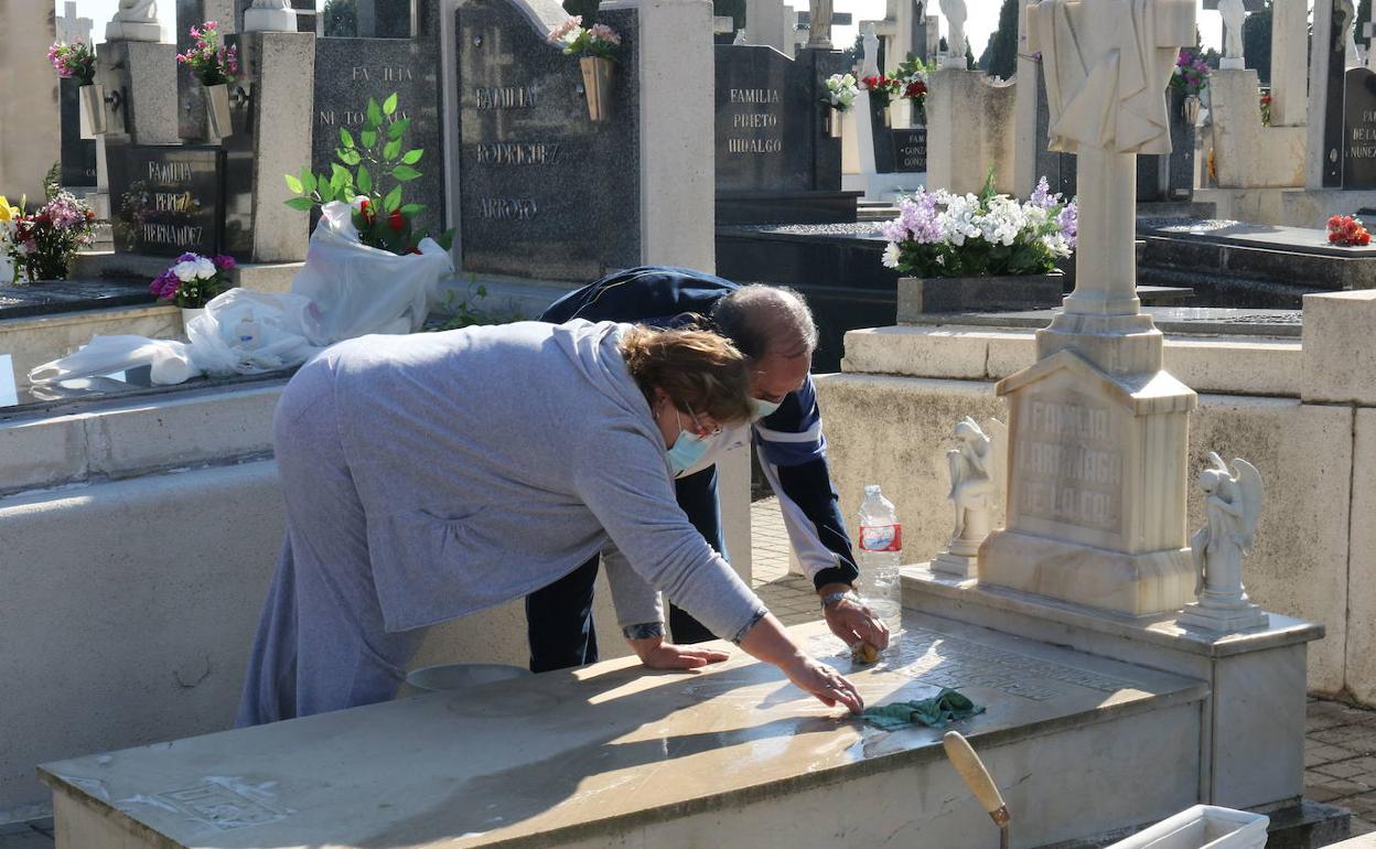 Una pareja limpia la tumba familiar en el cementerio del Carmen. 