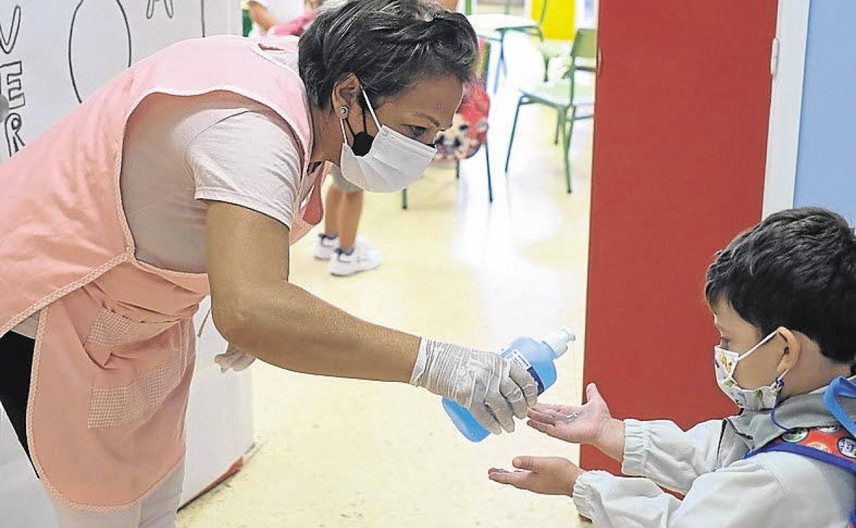 Una profesora proporciona gel a un alumno antes de entrar al aula.