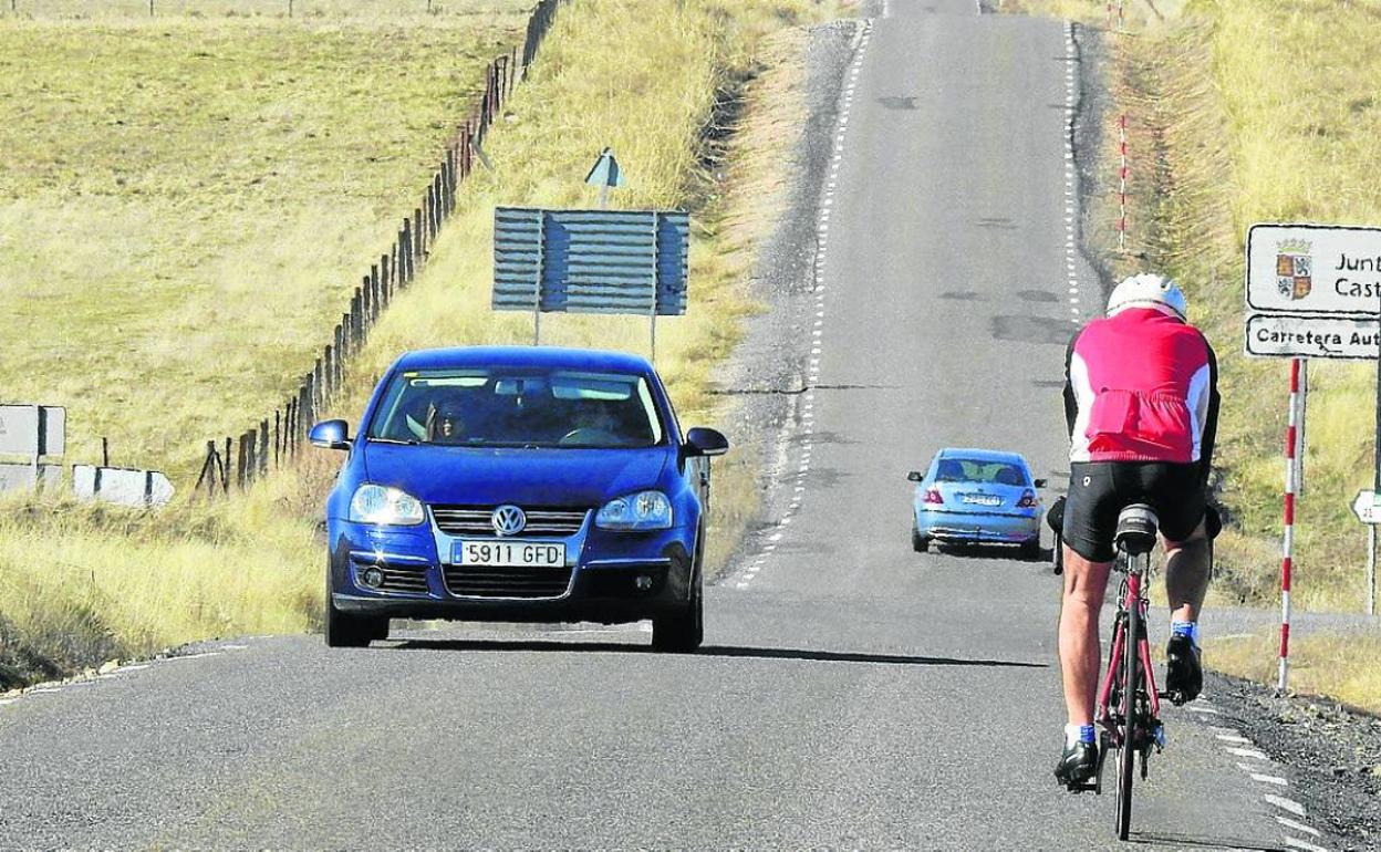 Ciclistas y coches circulan por la carretera entre El Espinar y Ávila. 