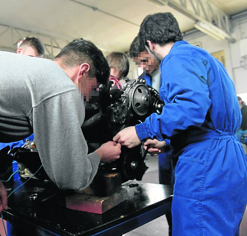 Cinco jóvenes participan en un taller prelaboral de automoción.