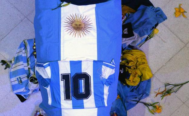 Aficionados presentan sus respetos al féretro de Maradona. 