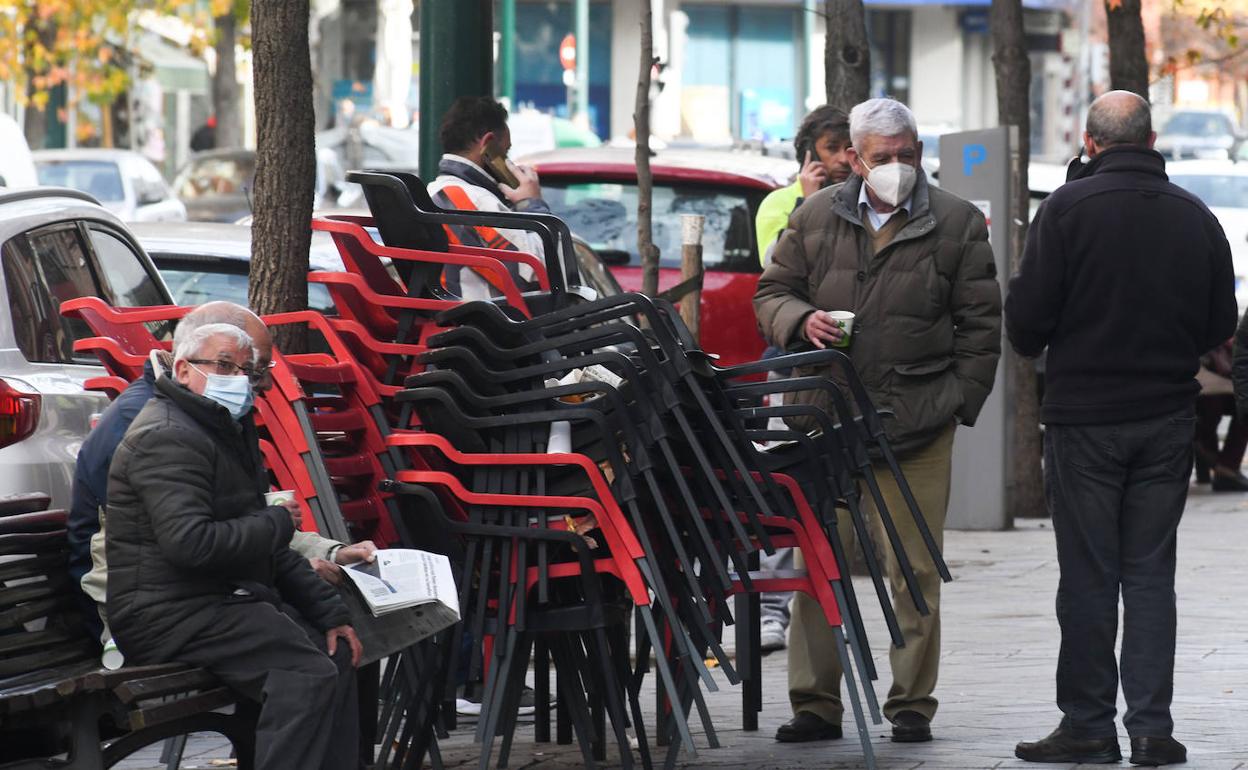 Un grupo de jubilados se sirven del mobiliario urbano y del bar para consumir en la calle.