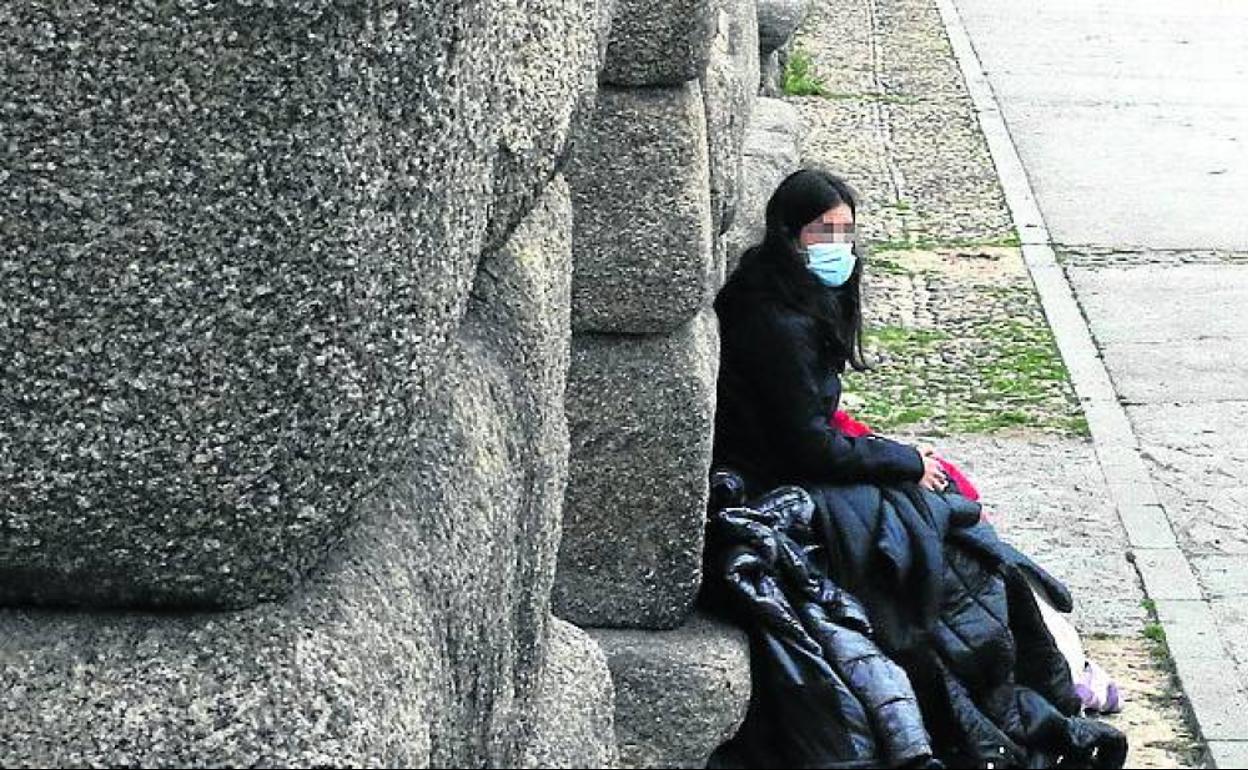 Una mujer se apoya en uno de los sillares del monumento. 