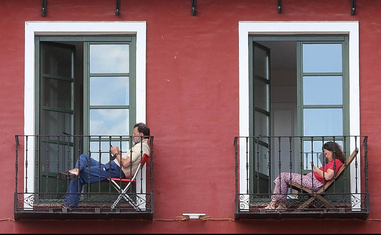 En la imagen dos vallisoletanos descansan en su casa de la Plaza Mayor de Valladolid durante el confinamiento.