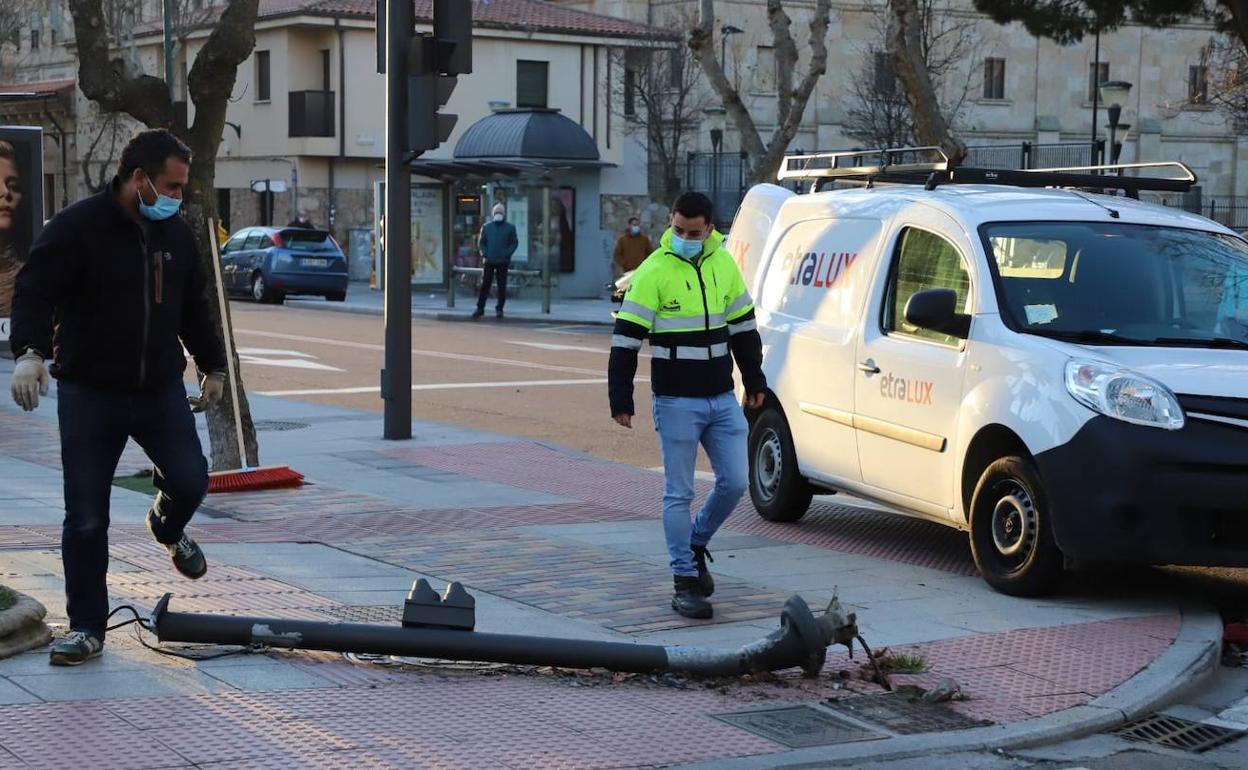 Los operarios comprueban el estado del semaforo derribado tras el accidente.