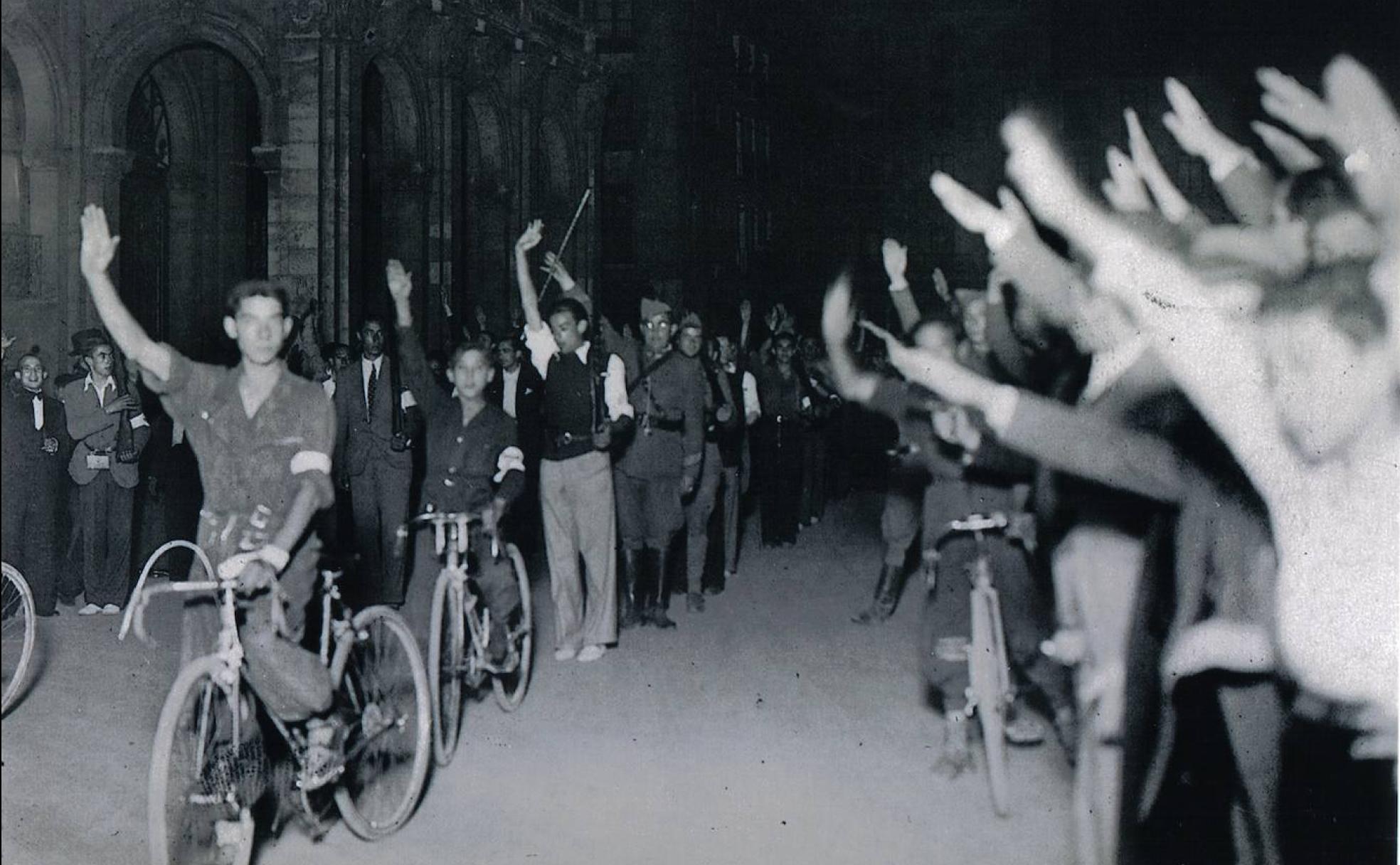 Vallisoletanos en bicicleta y a pie saludan con el brazo en alto en la Plaza Mayor de la ciudad el primer día de la sublevación.