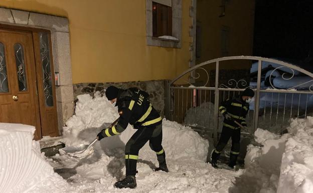 Dos soldados de la UME trabajan en la limpieza de los accesos a una casa en Posada del Valdeón. 